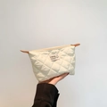 Cream white quilted clutch bag with diamond stitching and fashion label in hand - White