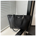 Detail der schwarzen Shopper-Tasche mit vertikaler Textur und weißem Markenetikett - Schwarz