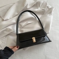 Bolso de hombro chic en charol negro con hebilla dorada sobre fondo de seda - Negro