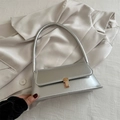 Bolso bajo el brazo plateado minimalista con cierre dorado sobre satén de color beige - Plateado