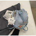 Détail du sac seau bleu clair avec cordon de serrage et bandoulière tissée - Bleu avec pendentif