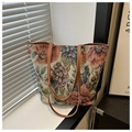 Detail eines Vintage-Jacquard-Blumenmusters und brauner Lederriemen einer Tragetasche - Rot