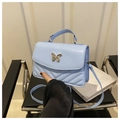 Detail of light blue crossbody bag featuring a golden butterfly clasp and V-shaped quilting - Blue