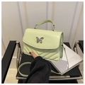 Detail of light green quilted handbag with silver butterfly buckle on black leather chair - Green