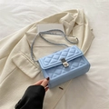 Sac bandoulière bleu clair matelassé avec chaîne argentée sur veste crème - Bleu