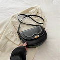 Minimalistische schwarze Leder Satteltasche mit goldener Metallschnalle auf beigem Blazer - Schwarz