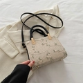 Borsa in paglia beige intrecciata con ricami floreali e manici neri in un contesto lifestyle - Nero