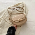 Elegante beige Satteltasche aus Leder mit goldenem Verschluss auf weißem Blazer - Khaki