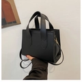 Detail of a black matte tote bag featuring decorative stitching and gold metal D-rings - Black