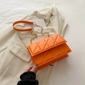 Orange quilted shoulder bag with gold chain strap displayed on light fabric - Orange