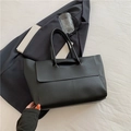 Classic black leather tote bag with flap closure on minimalist aesthetic background - Black