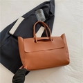 Brown leather tote bag with hollow handle and flap cover on white cloth surface - Brown