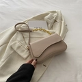 Bolso bandolera beige minimalista con cadena dorada sobre fondo de tela blanca fina - Caqui