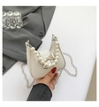Close-up of a chic cream-colored handbag featuring a large pearl handle and silver bow - White