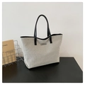 Detalle de bolso tote de lona crema con asas de cuero negro sobre una mesa de madera oscura - Negro