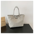 Detalle de bolso tote de lona con asas de cuero y logotipo metálico plateado al frente - Plateado