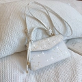 White mini handbag with golden star sequins and decorative knotted handle on fabric background - White