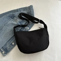 Minimalist black nylon crescent crossbody bag with adjustable strap on denim jacket - Black