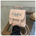 Macro detail of pink suede mini backpack showing silver butterfly metal ornament - Pink