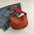 Minimalist rust red crescent cross-body bag with adjustable strap and nylon texture - Orange