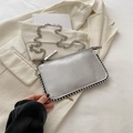 Borsa a mano argento metallizzato con rivetti indossata su un blazer chic - Argento