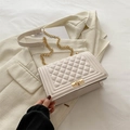 White quilted shoulder bag with golden chain strap and lock on neutral background - White