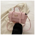 Detailed view of pink crossbody bag featuring a golden bow buckle on smooth PU leather - Pink