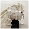 Dettaglio della mini borsa in pelle bianco crema con fibbia a fiocco dorato e trama liscia - Bianco