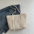 Borsa tote intrecciata beige con manici in ecopelle bianca su una superficie morbida - Bianco