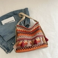 Boho-Stricktasche mit Ethno-Muster und langen Fransen auf lässigem Hintergrund - Orange