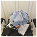 Detail of light blue bucket bag with silver butterfly accent and drawstring texture - Blue