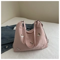 Detail van de roze tas met zilveren vlinderbedeltjes en een stijlvolle metalen ketting - Roze