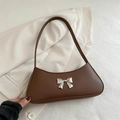 Bolso baguette marrón oscuro con lazo plateado sobre una chaqueta con textura - Marrón