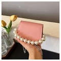 Detailed close-up of pink mini bag featuring pearl handle and silver chain strap - Pink