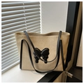 Détail d'un sac cabas en paille avec un nœud noir et des bandoulières en cuir élégantes - Noir