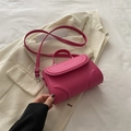 Magenta Umhängetasche mit Halbmond-Prägung und Silberbeschlägen auf beigem Blazer - Rosenrosa