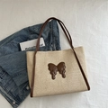 Large beige straw tote bag featuring a brown ribbon patch and leather handles - Brown