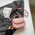 Bolso bandolera rosa con textura grabada y detalles dorados sobre un fondo de tela suave - Rosa