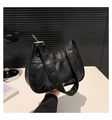 Detailed close-up of a black pleated hobo bag with wide strap and silver metal buckle - Black