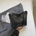 Bolso de hombro negro brillante minimalista con detalle de lazo en fondo de oficina - Negro