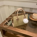 Beige corduroy crossbody bag with fluffy pompom detail and twin handles on wooden table - With Ornament / Khaki