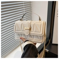 Detail of white quilted handbag featuring gold metal clasp and geometric triangle stitching - White
