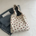Cremeweiße Cord-Einkaufstasche mit Erdbeermuster auf einer Denim-Jacke liegend - Weiß