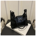 Detailed shot of a black glossy bucket bag featuring silver bow buckle and rope handle - Black