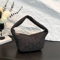 Black quilted floral hobo underarm bag with gold zipper on a dark wood and stone background - Black