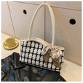 Detail of tweed check tote bag with leopard print ribbon bow on a wooden surface - White
