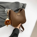 Brown faux leather half-moon shoulder bag with a plush monster charm and gold fashion logo - Brown with Pendant