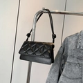 Classic black quilted crossbody bag with stylish knotted strap detail on metal rack - Black