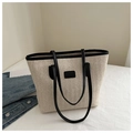 Detail of handwoven straw tote with black leather trim against denim background - Black