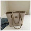 Detail view of woven straw tote bag texture with brown leather accents and top handles - Khaki